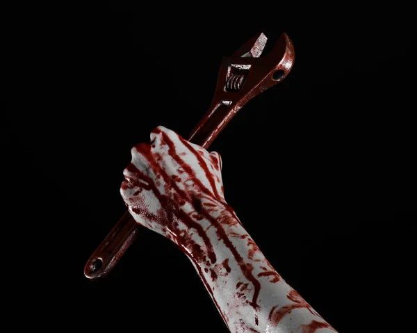 Halloween theme: bloody hand holding a big wrench on a black background