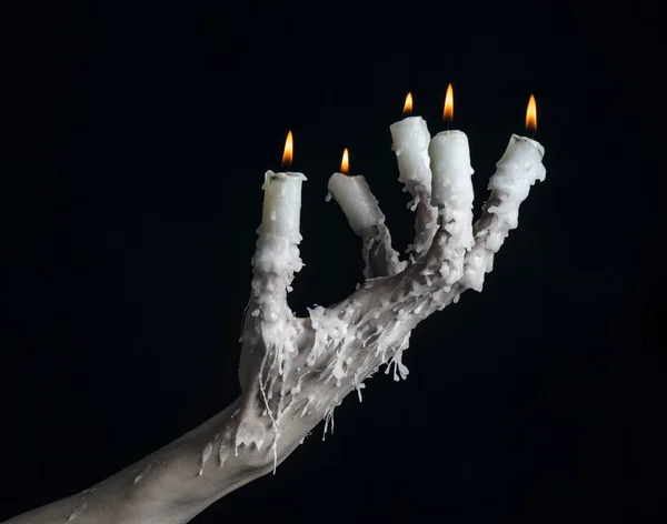 Halloween theme: on the hand wearing a candle and dripping melted wax on black isolated background