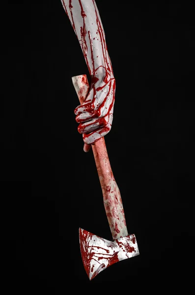 Bloody Halloween theme: bloody hand holding a bloody butcher's ax isolated on black background in studio