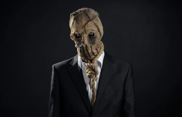 Fear and Halloween theme: a brutal killer in a mask on a dark background in the studio