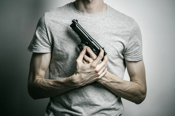 Horror and firearms topic: suicide with a gun on a gray background in the studio