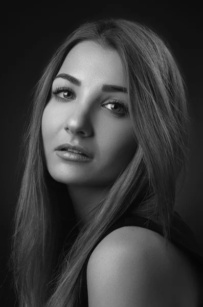 Dramatic portrait of a girl theme: Black and white portrait of a young beautiful girl on a dark background in the studio