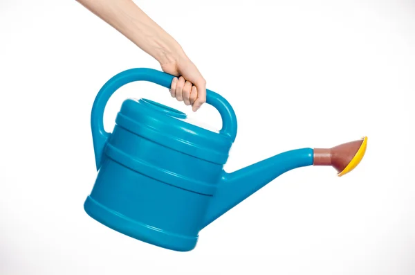 Caring for the plants and the garden theme: man's hand holding a large blue plastic watering can isolated on white background in studio