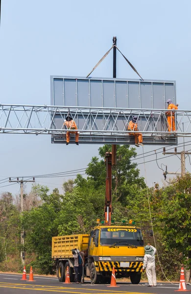 Workers install big steel billboard