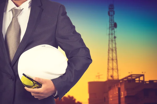 Engineer holding white helmet for workers security on background