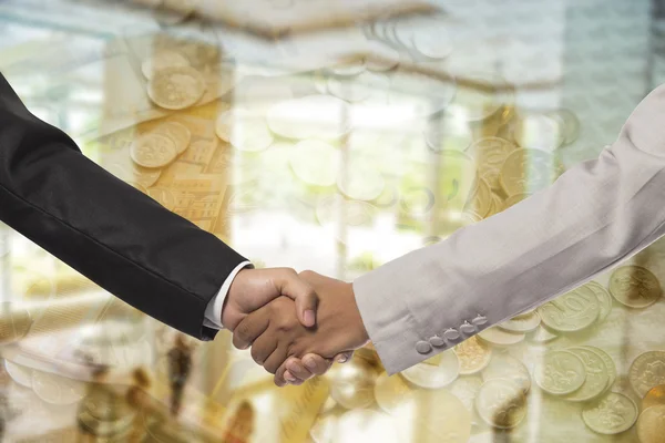 Image of business partners handshaking over business objects on