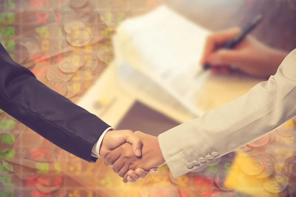 Image of business partners handshaking over business objects on
