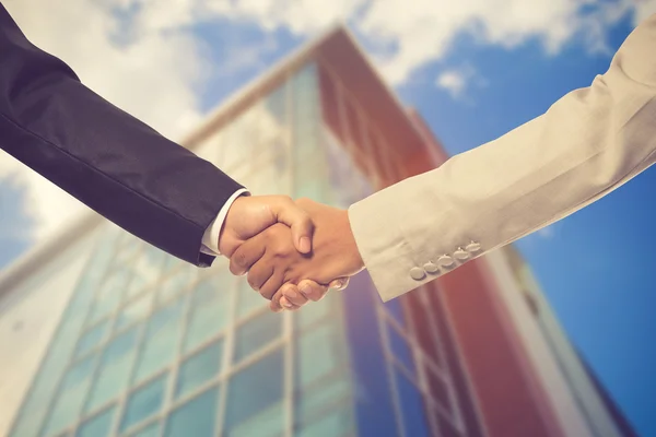 Close-up of business people handshaking on background of modern