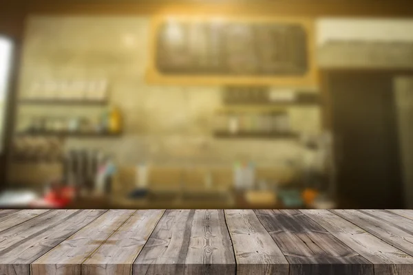Wood table top on blur background of coffee shop (or restaurant)