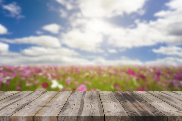 Wood top table on blur blue sky and cosmos flower background can