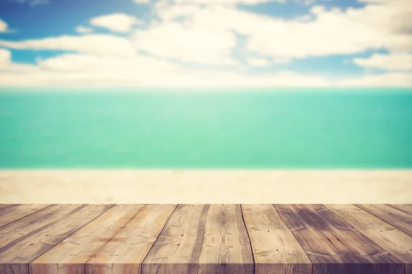 Wood table top on blurred blue sea and white sand beach backgrou
