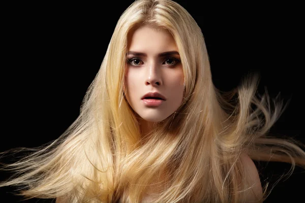 Portrait of blonde girl with flying hair on black background