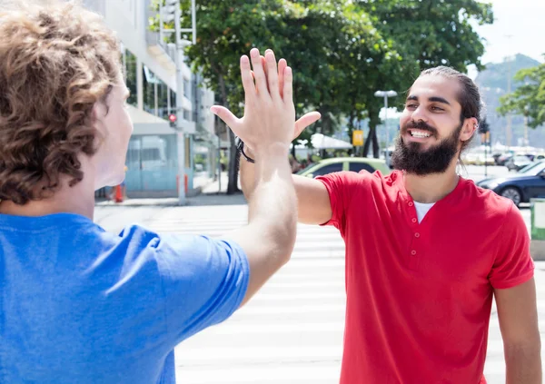 Man with beard give high five to caucasian guy