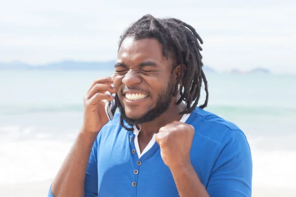 African american guy with dreadlocks receiving good news at phon