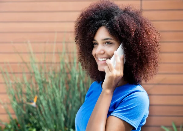 Laughing latin woman in blue shirt with phone