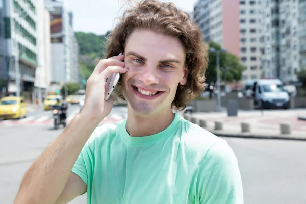 Caucasian guy with long hair at phone