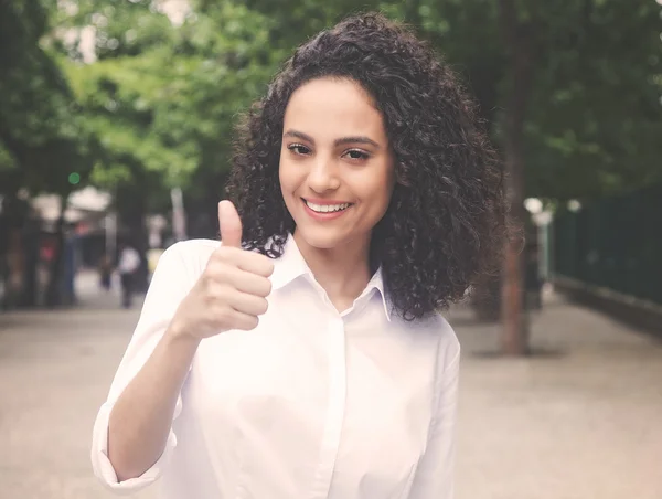 Caribbean woman in a park showing thumb up in vintage warm cinema look