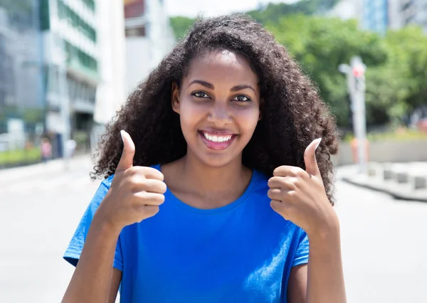 Latin woman with curly hair showing both thumbs
