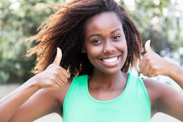 African american woman in a green shirt showing both thumbs