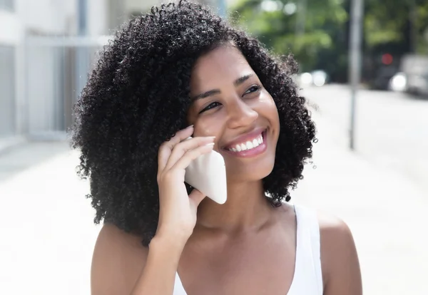 Laughing latin woman with curly black hair at phone