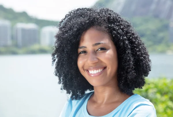 Laughing latin woman with curly black hair outdoor on a sea