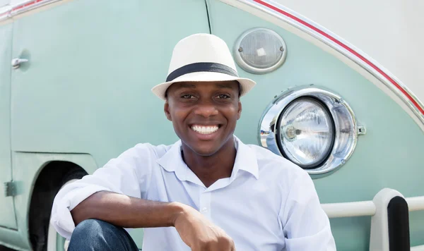 Resting man from Cuba with straw hat and old car