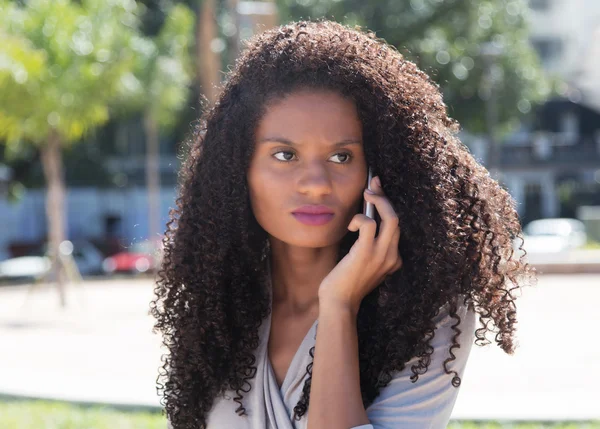 Thinking latin woman with long curly hair at phone