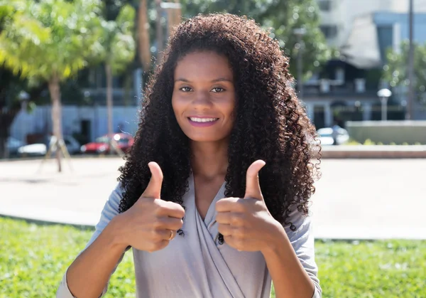 Latin woman with long curly hair showing both thumbs up