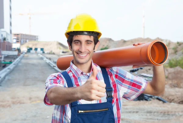 Hispanic construction worker with pipe at building site showing