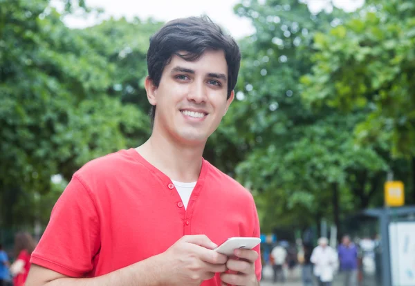 Handsome caucasian guy in red shirt using wifi with phone in a p
