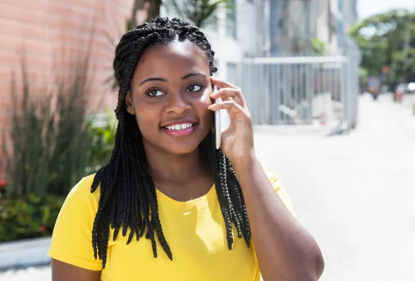 African american woman in a yellow shirt listening at mobile pho