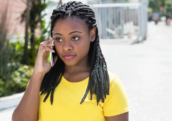 Beautiful african american woman in a yellow shirt listening at