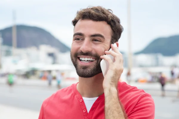 Laughing man with red shirt at cellphone in the city