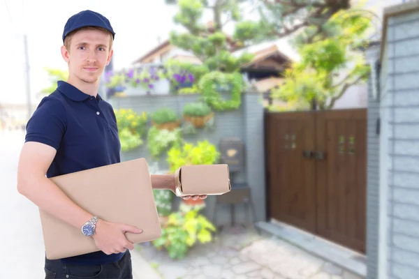 Delivery man carrying parcel delivery of boxes at to home.