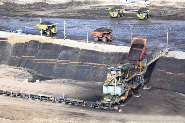 Heavy construction tipper trucks dump coal to the conveyor at co