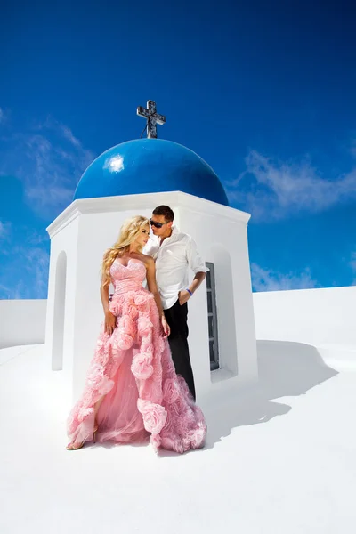 The lovely young couple beautiful woman from handsome man relating to the chapel with the blue roof in santorini