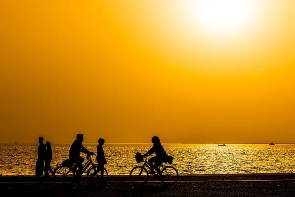 Silhouettes of people enjoying a walk by the seaside of the town