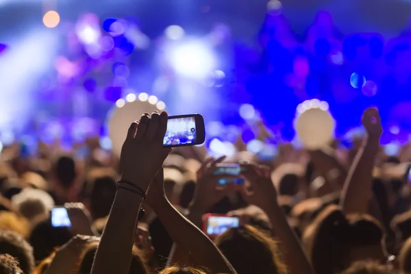 People taking photographs with touch smart phone during a music