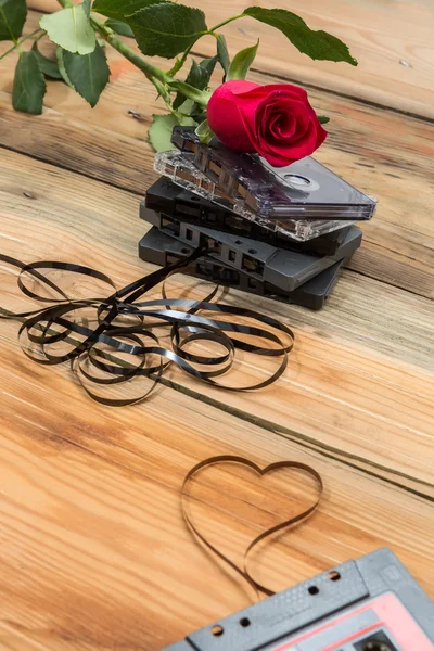 Rose and vintage audio cassette on a wooden background.