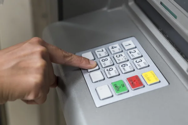 People stand in a queue to use the ATMs of a bank. Person receiv