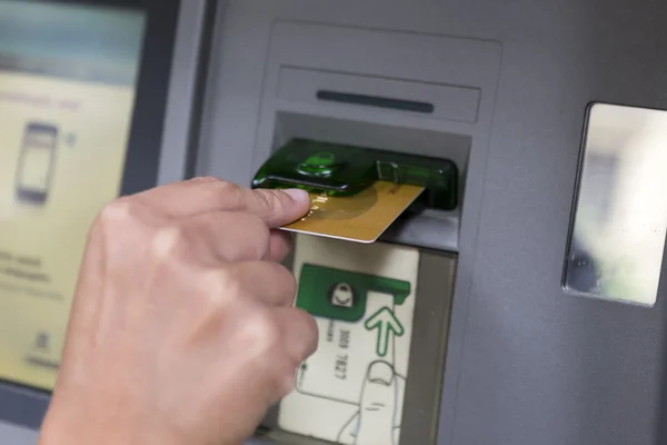 People stand in a queue to use the ATMs of a bank. Person receiv