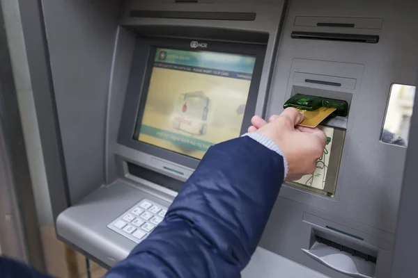 People stand in a queue to use the ATMs of a bank. Person receiv