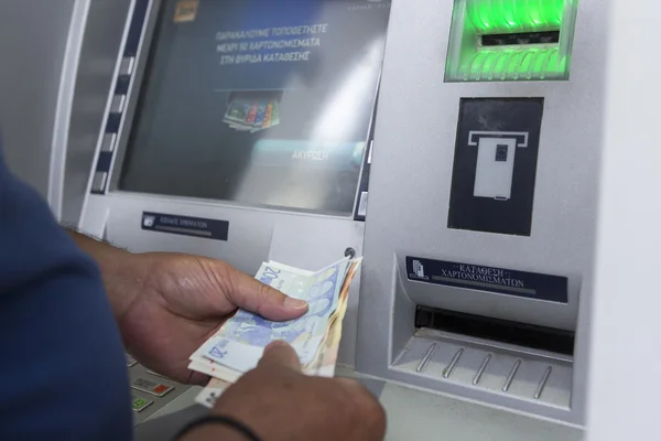 People stand in a queue to use the ATMs of a bank. Person receiv