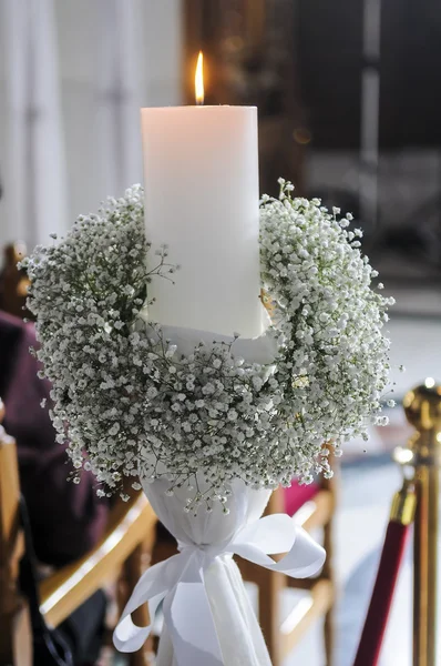 White candles and carnations flower wedding decoration in a chur