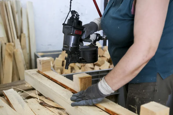 Craftsman puts nails in a piece of wood at a woodworking factory