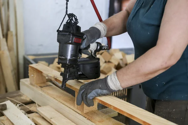 Craftsman puts nails in a piece of wood at a woodworking factory