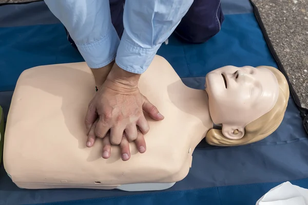 Man instructor showing CPR on training doll