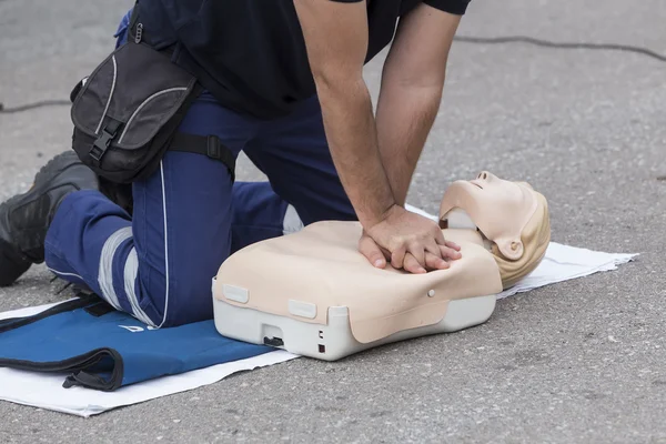 Man instructor showing CPR on training doll