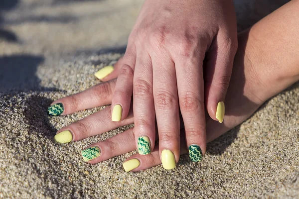 Female hand with beautiful nail polish playing with sand