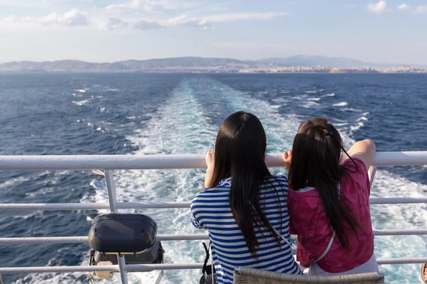Rear view of Tourists sitting on the deck of a ship, in Greece.
